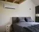 Vaillant Klimaanlage montiert an der Wand über einem Doppelbett mit grauer Bettwäsche und dekorativen Kissen. Ein Nachttisch steht daneben.